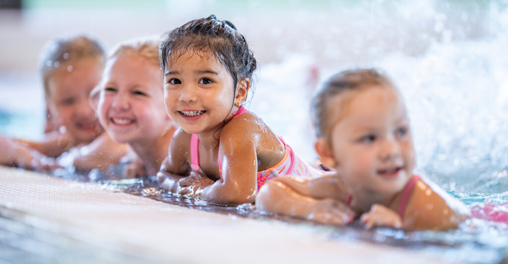 Kleinkinder im Schwimmbecken, angelehnt an den Beckenrand